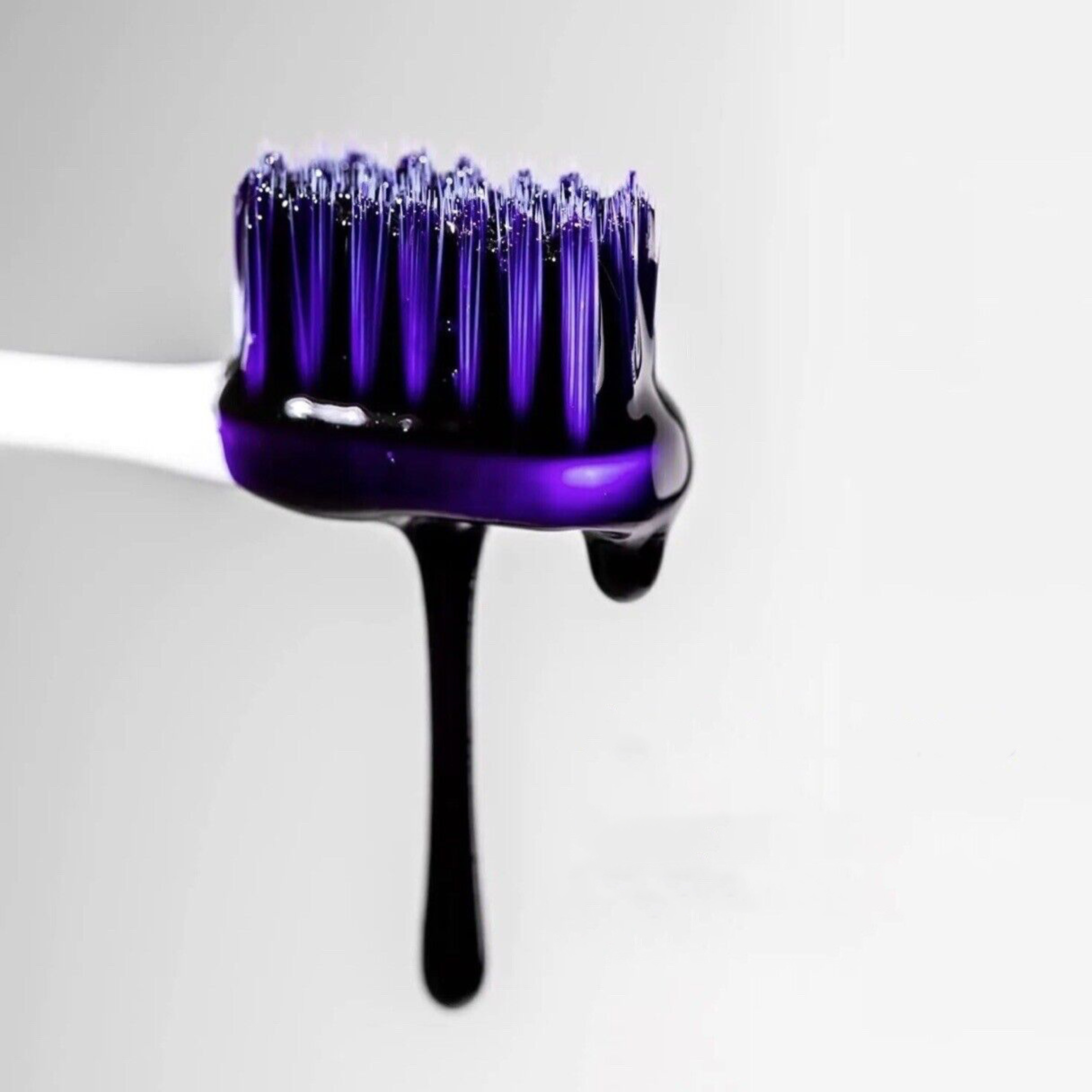 Toothbrush with purple toothpaste dripping from it