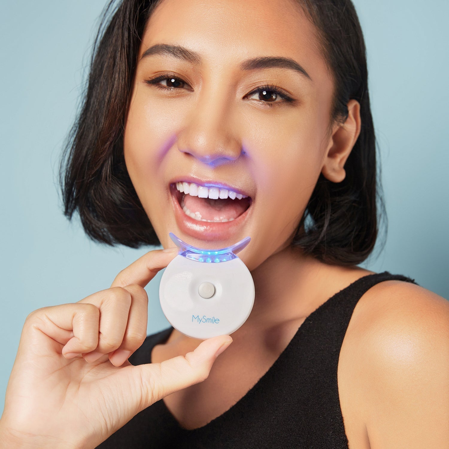 Woman smiling and holding a MySmile teeth whitening device